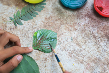 kid doing art work with watercolor for making pattern of nature by leaf of treeの写真素材