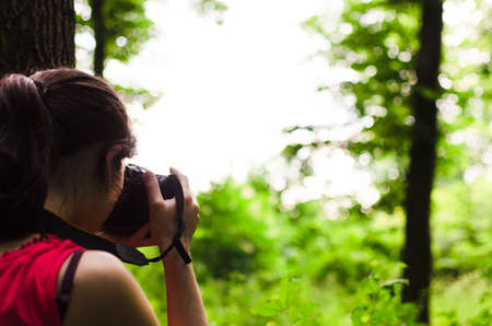 Girl photographer taking photos in forest