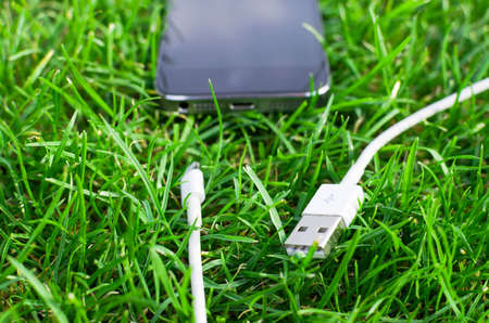 Phone detail with cable on grassの写真素材