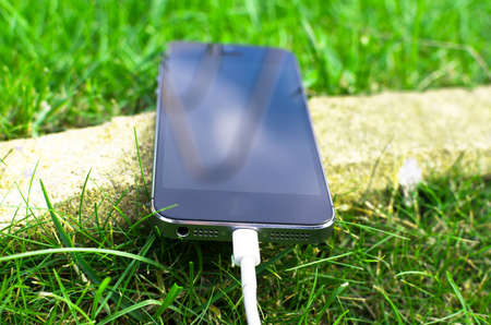 Phone detail with cable on grassの写真素材