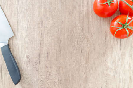 Tomato with knife on wooden tableの写真素材