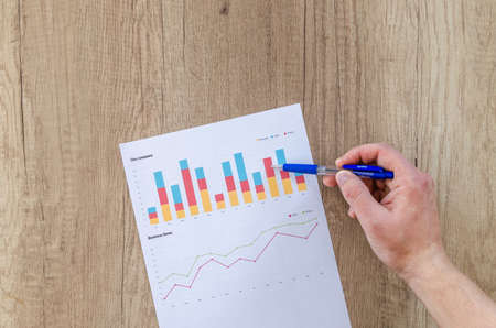 Man showing business graph on wooden tableの写真素材
