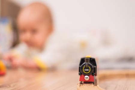 Baby is playing on the floor with toys and small train arrives