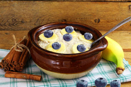 Oatmeal porridge in bowl topping with banana blueberriesの写真素材