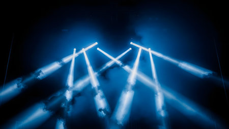 Multiple bright blue spotlights crisscross and fan out across a smoky, dark environment, creating a vibrant and dynamic light show effect, perfect for concerts or events.の素材