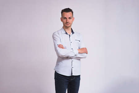 portrait of a cute young brunette man on a white background in different poses with different emotions. He stands directly in front of the camera and shows different emotionsの写真素材