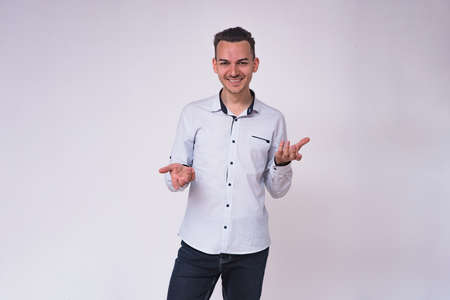 portrait of a cute young brunette man on a white background in different poses with different emotions. He stands directly in front of the camera and shows different emotionsの写真素材