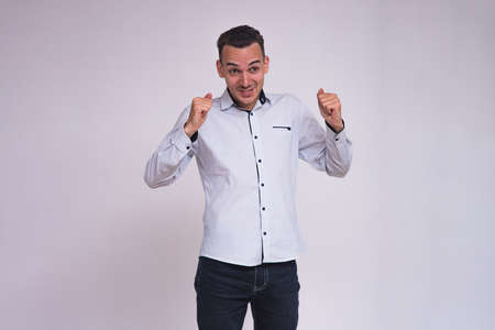 portrait of a cute young brunette man on a white background in different poses with different emotions. He stands directly in front of the camera and shows different emotionsの写真素材