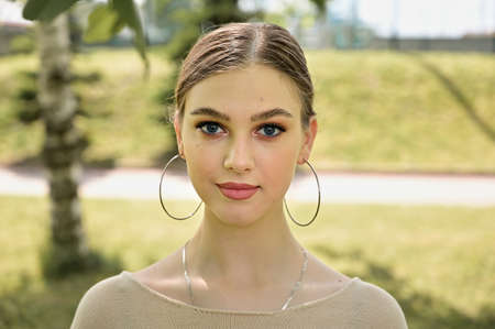 Model posing in a city park in sunny summer weather. Close-up portrait of a cute caucasian young...