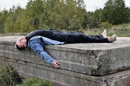 The concept of devastation and sadness. Photo of a lying man in ruins outdoorsの写真素材