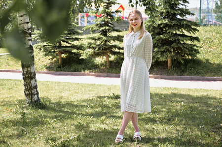 A photo of a pretty blonde in a park shows happiness. Model posing with a smile in sunny weather...