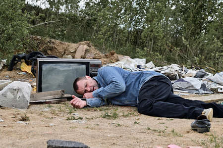 Photo of a caucasian homeless man lying in the trash. Environmental protection conceptの写真素材