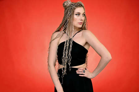Portrait of caucasian fashionable woman in black blouse with long afro dreadlocks hair in studio....