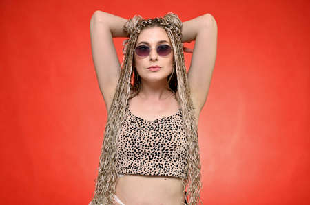 Pretty model with glasses posing on a red background standing right in front of the camera. Portrait...