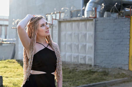 Close-up portrait of a caucasian fashionable woman with long hair afro dreadlocks in the city. Pretty model posing in clear weather.の写真素材
