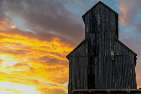 Landscape photo in the orange setting sun of abandoned old buildings in autumn against the backdrop of a dramatic skyの写真素材