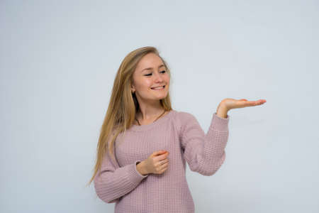 beautiful smiling girl holding her hand open against a white background with long hairの写真素材