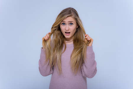 Scared beautiful girl holding her hair on a white backgroundの写真素材