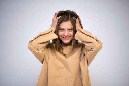 beautiful girl holding her head smiling over a white backgroundの写真素材