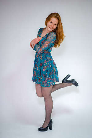 Beautiful young woman with red hair standing in front of her arms on white backgroundの写真素材