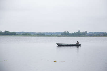 Fisherman rows the wooden boat in lakeの写真素材