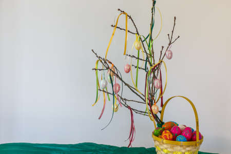 Easter eggs in basket and branch with ribbons on the white backgroundの写真素材