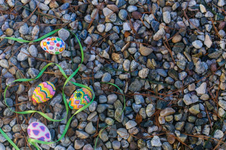 Easter eggs and green ribbon lie on the pebblesの写真素材