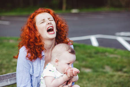 baby bites hand of mother. concept of loving mother and child. mother playing with baby.の写真素材