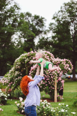Beautiful moment of mother and her little kid playing together in the flowers garden.の写真素材
