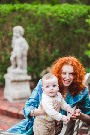 Loving mom carrying of her newborn baby. Mother and child in the garden. Family having fun together.の写真素材