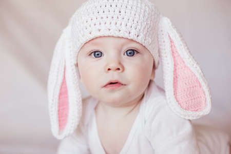 Cute funny baby with bunny ears at home on a white background. Easter greeting card. Baby easter bunnyの写真素材