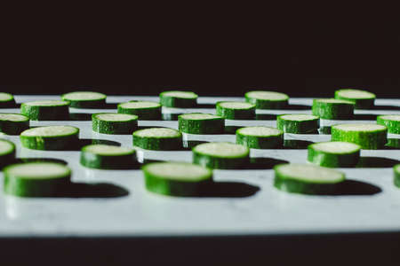 zucchini slices on a table with shadowsの写真素材