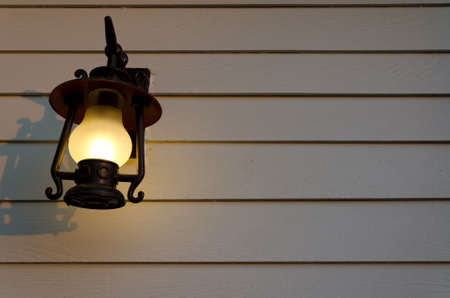 Lamp is shining gently on the white wooden wallの写真素材