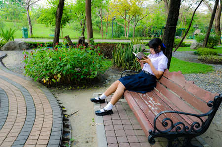 Thai high-schoolgirl reading in the park. She is relaxingの写真素材