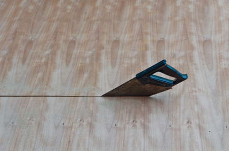 A saw is sawing through the wooden board.の写真素材