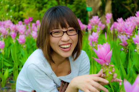 Cute Thai girl are very happy with flowers (Siam Tulip). She is laughing with joy.の写真素材