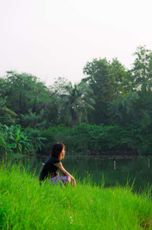 Cute Thai girl is letting her mind flow across the river bank in the rural area of Thailand の写真素材