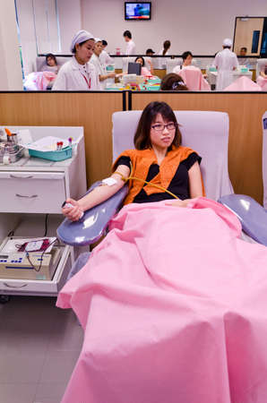 Thai girl is donating blood in the red cross institution with other donators のeditorial素材