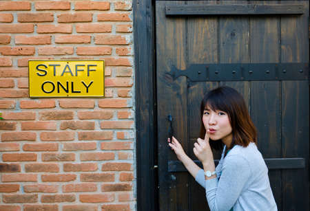Cute Thai woman is trying to enter the staff room, which is a forbidden area.の写真素材