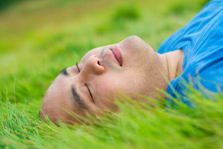 Man lying on soft green grass, relaxing with pleasureの写真素材