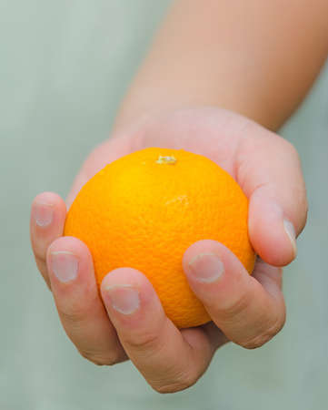 Here is an orange for you. A person is handing an orange for you.の写真素材