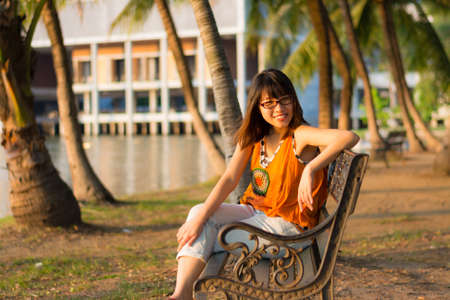 Cute Thai girl is relaxing near the riverside under the shade of the palm treesの写真素材