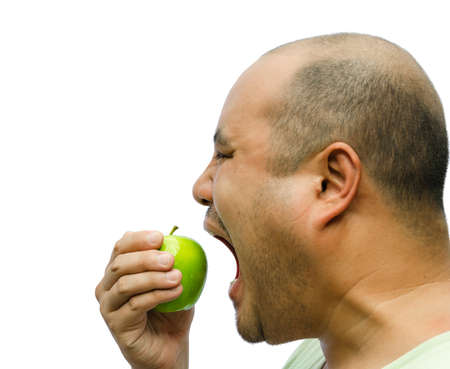 A fat man is forcing himself to eat an apple on white backgroundの写真素材