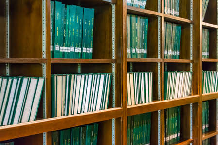 Row of green thesis in the large bookshelf in Chulalongkorn university of Thailand. It is full of Master degree knowledge.のeditorial素材