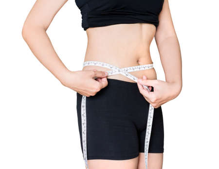 A woman is measuring her waist with a tapeline in white isolated backgroundの写真素材