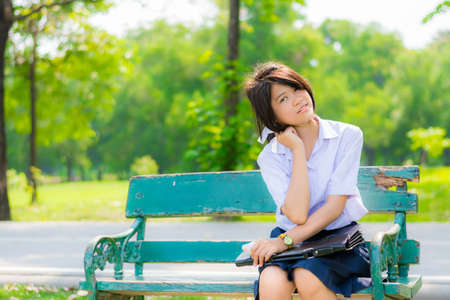 Shy Thai schoolgirl sitting on a bench in the park  closeup の写真素材