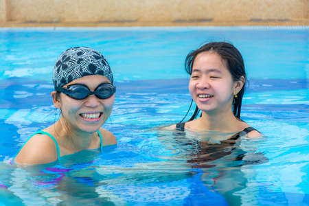 Two Asian girls are having fun floating in the swimming pool in holiday relaxationの写真素材