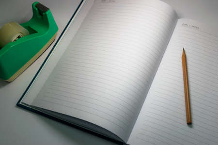 Still life notebook and other stationery tools such as pencil and adhesive tape in dim light 