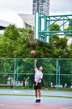 BANGKOK, THAILAND - 22 JULY 2014  Thai student is doing a layup shoot in public basketball court on July 22, 2014 のeditorial素材