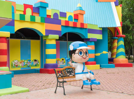 Colorful toy town building with coloful blocks and a boy cartoon character greeting on the benchのeditorial素材